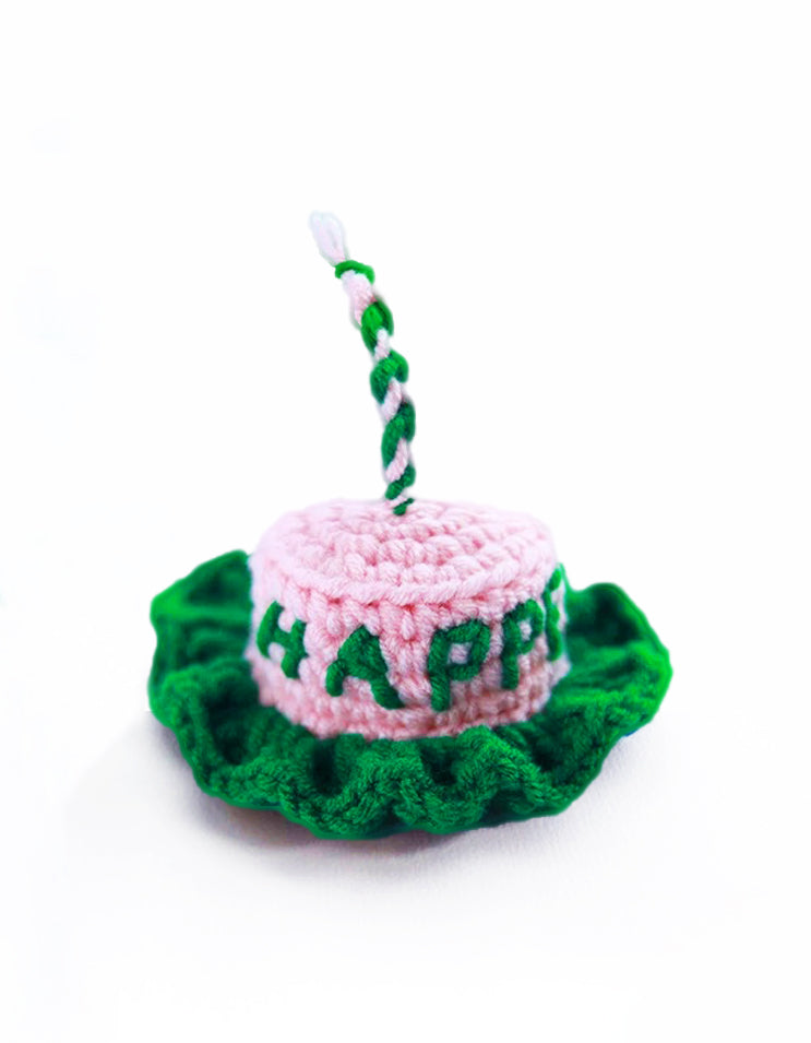 close-up of pastel pink and green knitted pet birthday hat with cake-inspired design and soft texture