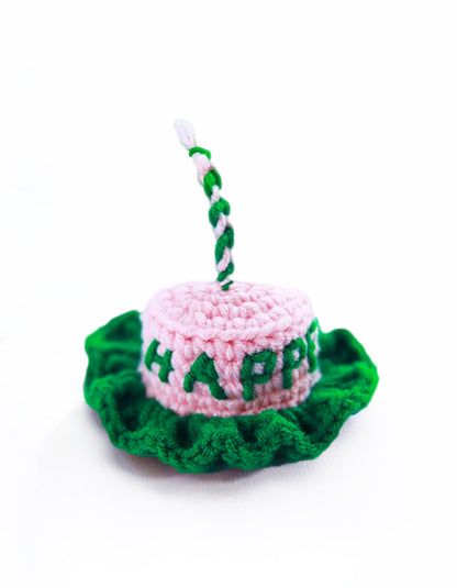 close-up of pastel pink and green knitted pet birthday hat with cake-inspired design and soft texture